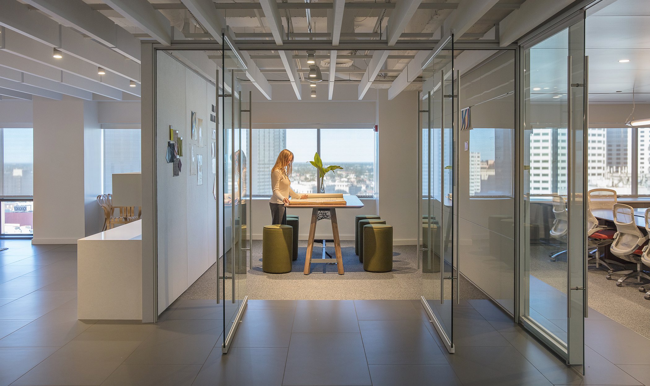 Business woman pointing at sticky note to female colleague on glass wall in office. Business people working on project together.